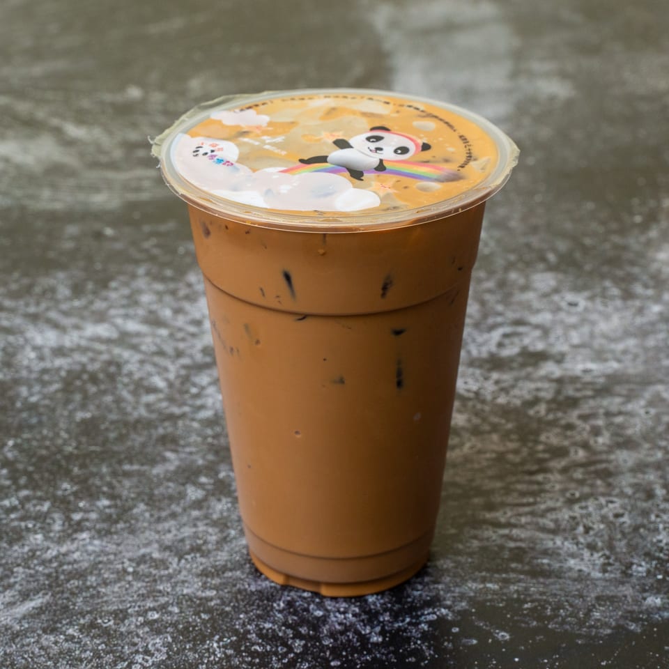 Iced brown beverage in a clear plastic cup with a panda and rainbow lid.